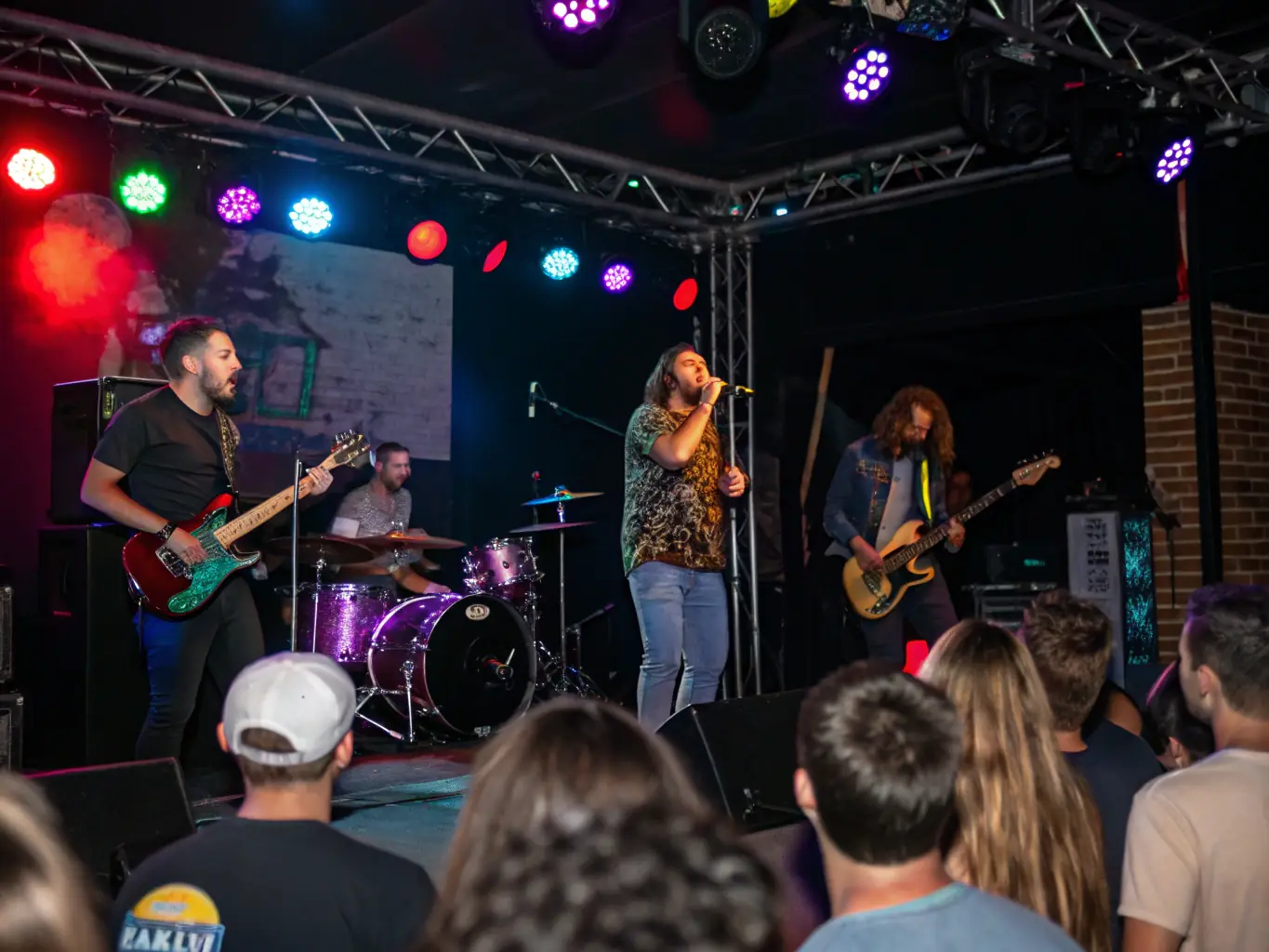 A vibrant photograph capturing a live musical performance during one of ASSO ENSEMBLE MAX PINCHARD's Cultural Performance Series events, showcasing musicians passionately playing their instruments on stage with an engaged audience in the background.